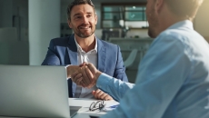 Two people shaking hands from opposite sides of the table